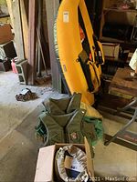 Photo of inflated yellow inflatable fishing raft standing upright with two green lifejackets in front and a box containing inflator device down below.