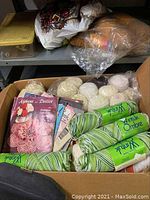 Wide view of box containing assorted skeins of yarn and knitting instruction books.