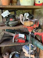 Shelf showing Craftsman chainsaw, Homelite trimmer, and weedwhacker with visible dust and weathering.