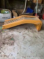 Side view of a single orange metal auto repair ramp showing perforated top surface and wear.