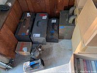 Photo of multiple metal tool boxes, large magnet, compressor parts on floor in garage corner