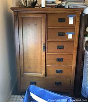 Front view of wooden standup dresser showing six drawers and cabinet door with metal handles.