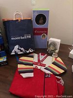 Lot overview showing American Girl doll box, traditional Korean child's costume laid out, shopping bag, and small figurines.