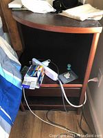 Wooden nightstand showing curved top surface with wear and items on shelves.