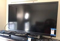 Front view of Sony Bravia LCD TV with remote and cables on stand