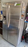 Front view of stainless steel side-by-side refrigerator with vertical handles and dispenser on left door