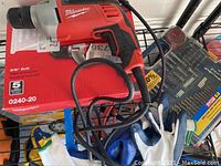 Milwaukee 3/8 drill placed on top of its original red box with visible model number 0240-20 and 5-year warranty info.