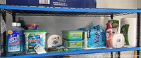 Shelf with assorted cleaning and dishwashing products including Jet-Dry, Cascade pods, Swiffer refills, Kirkland paper towels