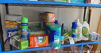Wide view of assorted cleaning supplies and disposable household items on metal shelving.