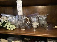 Wooden shelf displaying lot items with jade grapes, metal baskets, glass coasters, and ceramic container
