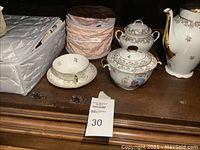 Full view of the tea set displayed on a wooden surface, showing all items in the lot including teapot, sugar bowl, covered dish, and teacup with saucer.
