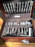 Wooden chest open showing Seibu flatware set with knives on top rack and forks, spoons below.