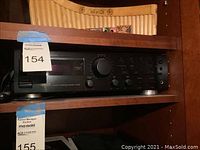 Front view of the JVC stereo component on wooden shelving with auction tag visible.