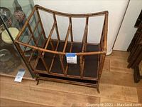 Rattan magazine rack shown from front, highlighting vertical dividers and base.