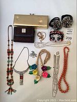 Full collection showing all items: Betty Boop wallet, gold-tone clutch purse, brown wallet, beaded and wooden jewelry, and earrings arranged flat on a surface.