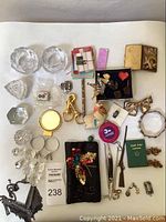 Overview of the entire assortment showing Costa Boda candle holders, various costume jewelry, accessories like measuring tape and compact mirror.