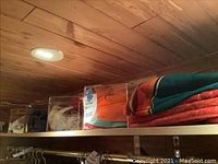 Photo of two clear acrylic hat boxes and folded colorful fabric items on shelf