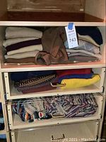 Drawer of folded sweaters in neutral, earth-tone and colorful patterns.