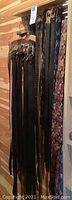 Photo showing multiple men's leather belts hanging on wooden wall, varied brown and black colors with different buckle styles