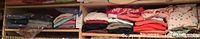 Shelf with folded assorted knit tops and pajamas in various colors and prints, some Hanes men's pajamas in plastic bags