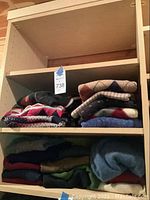Stacked sweaters on shelving unit showing various folded sweaters in different colors and patterns