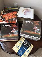 Multiple stacks of vinyl records on a table. Visible front covers include Disco Life Vol 2, Toronto, Le Conteau de Capucins, and a few others.