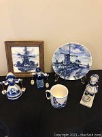 Overview of collection: framed tile, decorative plate, Dutch figure salt and pepper shakers, mug, and candle holder