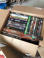 Open cardboard box shows DVDs with titles including Patton, Walker Texas Ranger, The Duke, Ghostbusters, Knight Rider