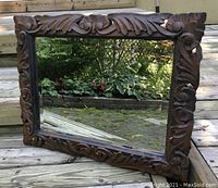 Full view of the vintage mirror showing carved wooden frame and beveled glass.