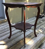 Side view showing the table's curved legs and scalloped carved apron.