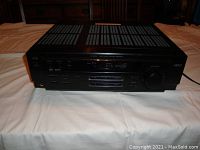 Front view of JVC RX-6010VBK receiver showing control buttons, sliders, display, and volume knob.