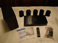 Full view of the entire system including Blu-ray player, subwoofer, five speakers, remote, and manuals.