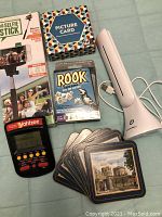 Lot items laid out on green surface showing games, selfie stick, coasters, and lamp