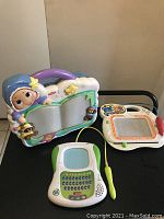 Photo of three children's toys: crib mobile, LeapFrog educational toy, and VTech educational toy