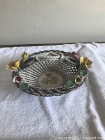 Angled side view of the vintage ceramic basket showing the woven pattern, handle, and floral decorations around the rim.