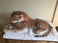 Side view of the large plush tiger lying on a white towel, showing detailed stripes and facial features.
