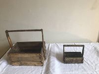Two antique bamboo baskets displayed side by side on a white cloth, showing size difference and handle structure.