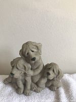 Front view of the three Quarry Critters stone dog figurines showing their facial features and grouping.