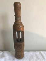 Front view of antique wooden wine bottle cork driver showing spindle inside carved wooden frame and rounded handle.