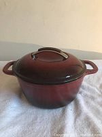 Closed KitchenAid cooking pot showing full pot and lid in red enamel with metal handle on lid.