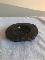 Top and angled view showing dark alabaster ashtray with carved texture and central bowl