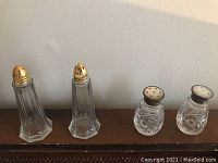 Pair of hexagonal clear glass salt and pepper shakers with gold-tone metal tops