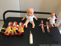 Full lot showing all items on black surface: 3 Ronald McDonald finger puppets, 2 large rubber dolls, 2 small naked dolls, and 1 baby bottle.