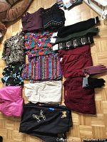 Photo of assorted ladies clothing including tops and gloves in various colors and patterns mostly sizes large to 1X, condition good.