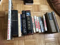 Photo showing twelve assorted war-related books on a parquet floor, titles visible.