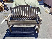 Front view of weathered solid wood garden bench showing slatted seat and backrest with carved rose motif