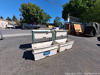 Front view of two white plastic containers showing 'California Grown' sticker, outdoors on asphalt surface.