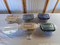 Photo of six plastic storage containers with handles arranged in two rows. Containers are individually wrapped in plastic and vary in translucent colors.