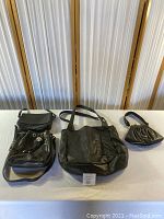 Three black leather purses of various sizes displayed on a white table.