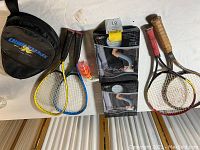All items displayed on a table including tennis rackets, badminton rackets with case and shuttlecocks, workout shorts in boxes
